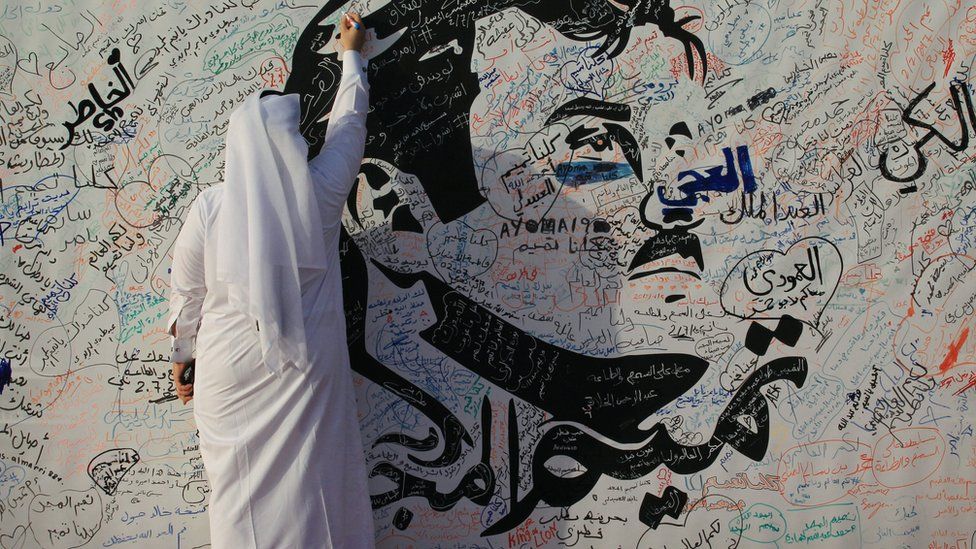 A man writes on a painting depicting Qatar's Emir Sheikh Tamim Bin Hamad Al Thani in Doha, Qatar (2 July 2017)