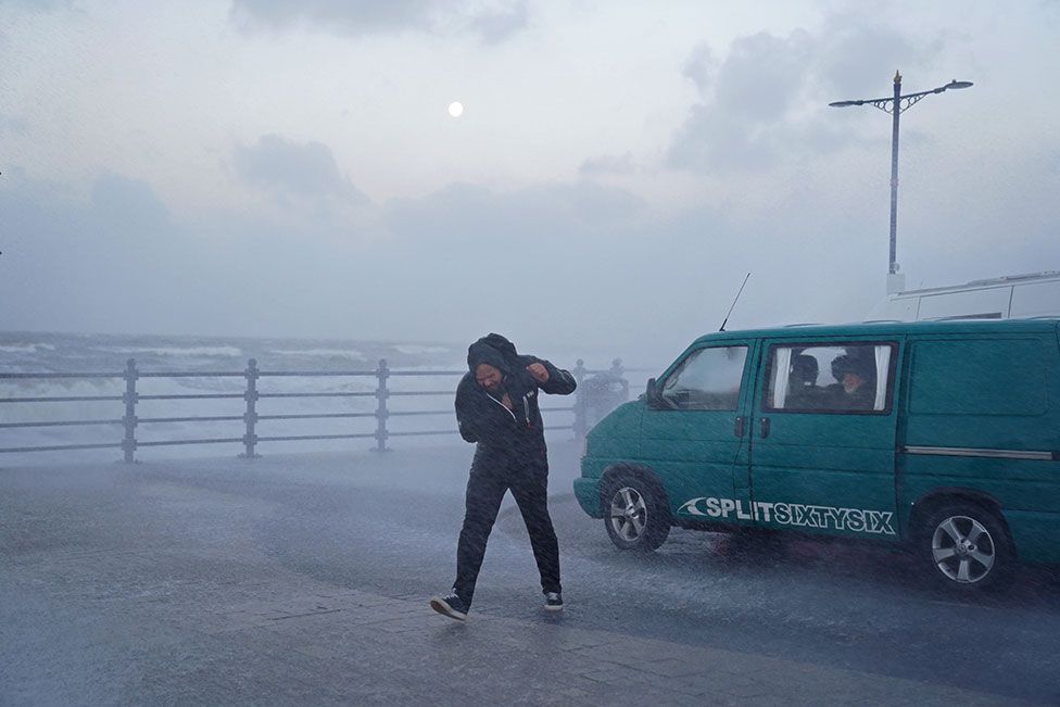 A person fights against the wind on the seafront in Porthcawl, Bridgend, on 18 February 2022