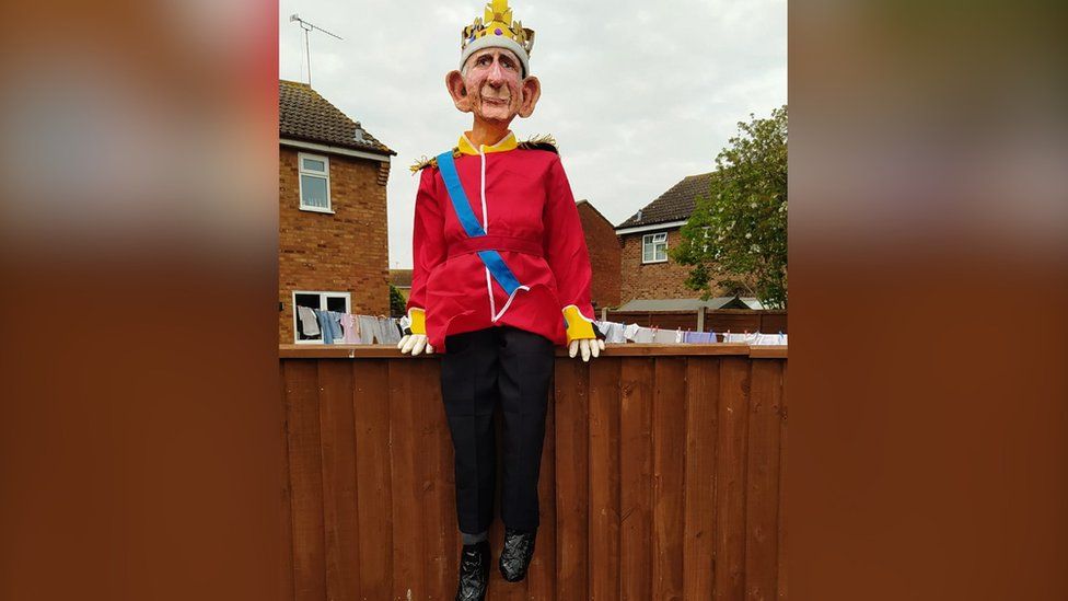 Model of King Charles sitting on a garden fence.