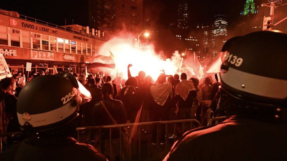 Smoke rises over a group of protesters in New York