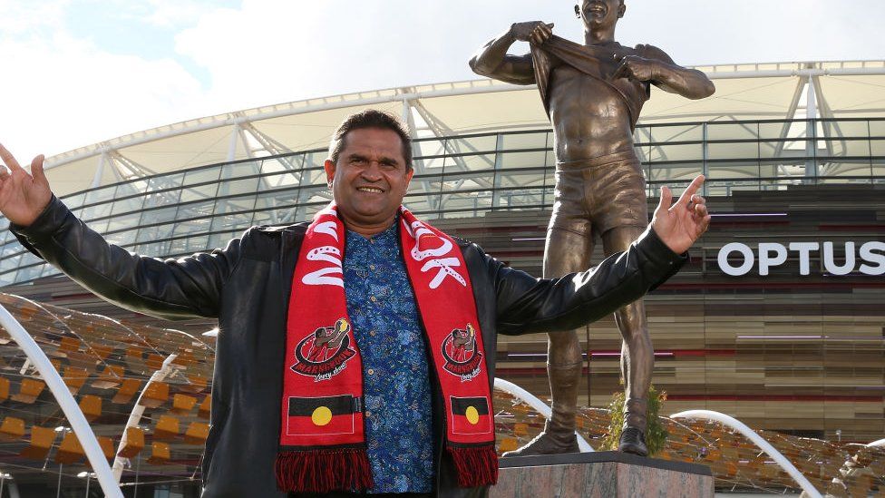 Nicky Winmar with a statue depicting his 1993 stand against racism, in 2019