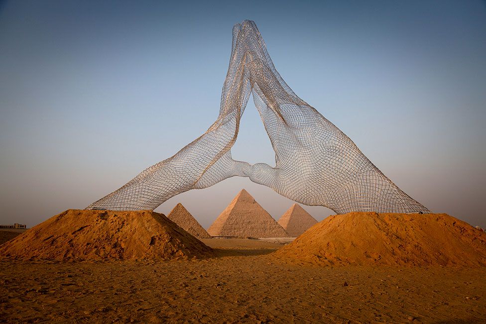 An installation entitled Together, by Lorenzo Quinn, is displayed next to the Great Pyramids of Giza in Cairo, Egypt