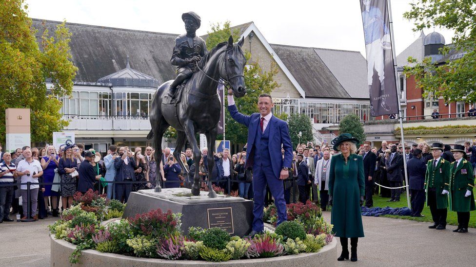 Jockey Frankie Dettori poses for a photo with a statue of himself created by Tristram Lewis after being unveiled by Queen Camilla