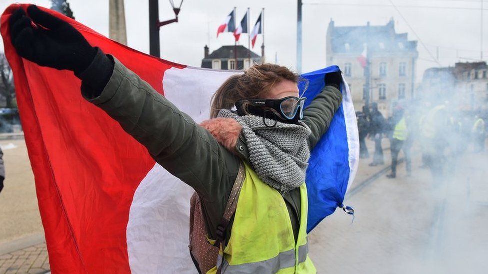 A protester holds a French flag during an anti-government demonstration called by the "Yellow Vest" (Gilets Jaunes) movement on January 12, 2019, in Le Mans, western France