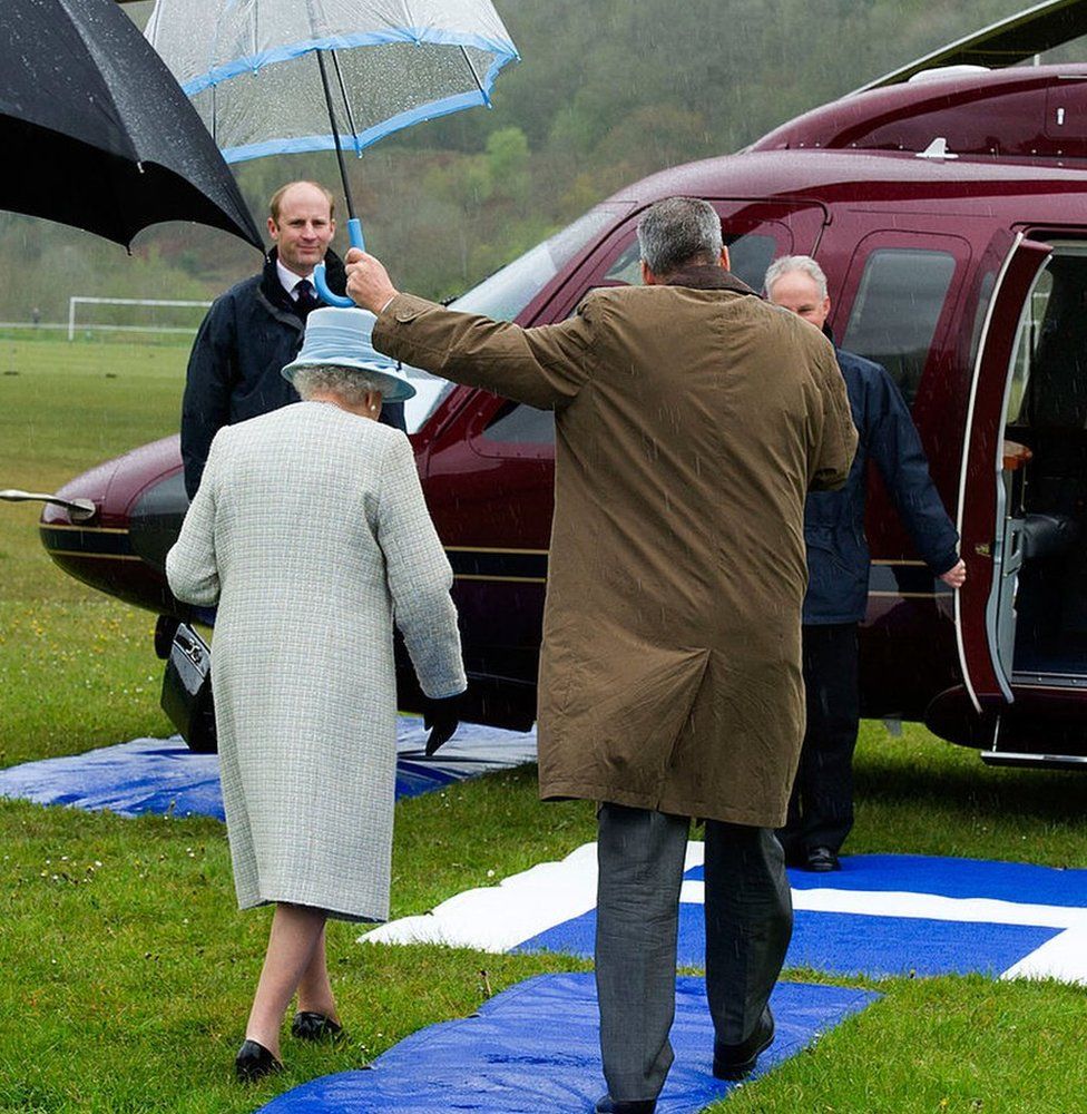 Queen Elizabeth II is sheltered by an umbrella as she walks to the royal helicopter after officially opening Ynysowen Community Primary School on April 27, 2012 in Aberfan
