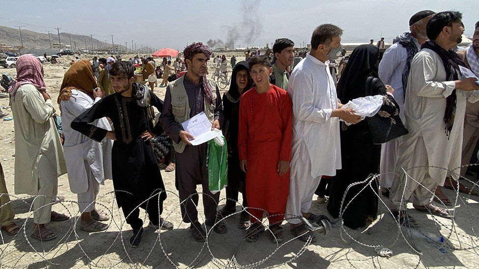 Afghans including those who worked for the US, NATO, Europe Union and the United Nations in Afghanistan wait outside the Hamid Karzai International Airport to flee the country