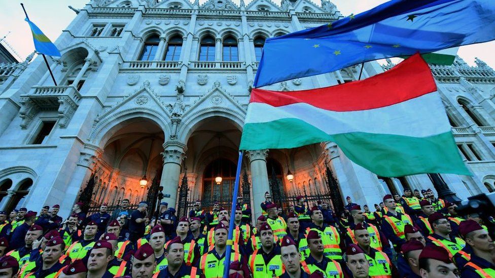 People protest in front of lines of police officers at the parliament building at Budapest