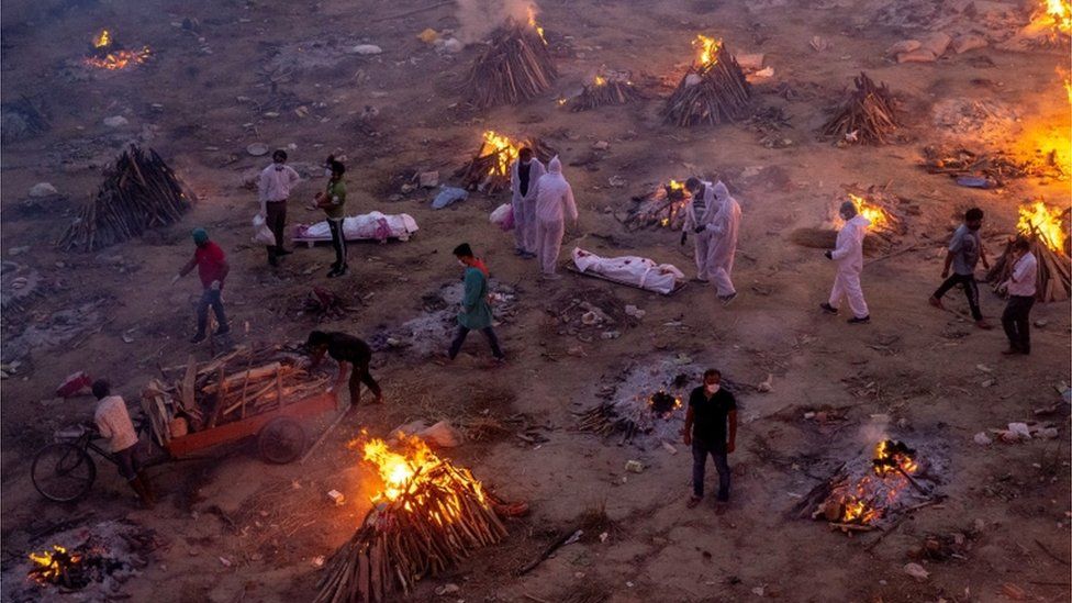 Люди проходят мимо погребальных костров в Нью-Дели, Индия, апрель 2021 года