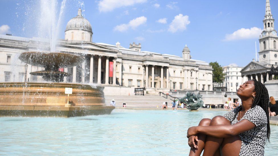 A woman relaxes in the sunshine at the fountains in Trafalgar Square in London, Britain 11 August 2020.