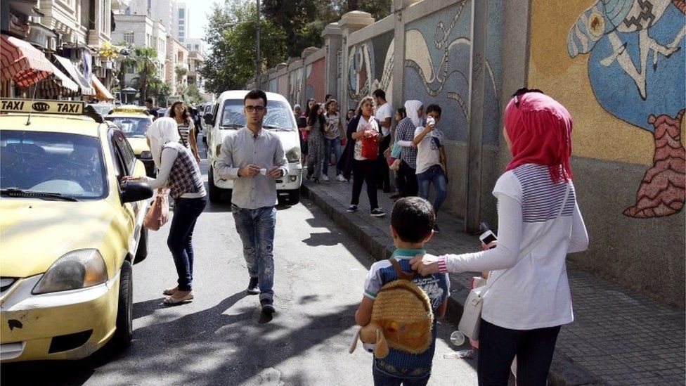 Syrian parents accompany their children as they come out of their school in Damascus, Syria, 18 September 2016. Some four million Syrian students started their school year in around 15,000 schools across the country.