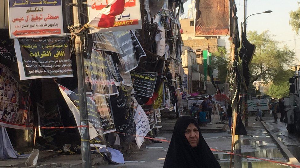 An Iraqi woman walks at the scene of a devastating IS attack