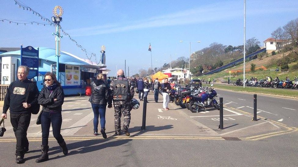 People walking along Southend seafront with motorcycles also in the image