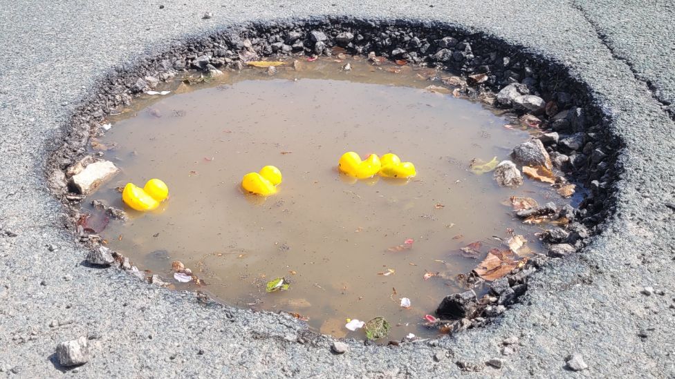 The flooded hole with rubber ducks floating on it