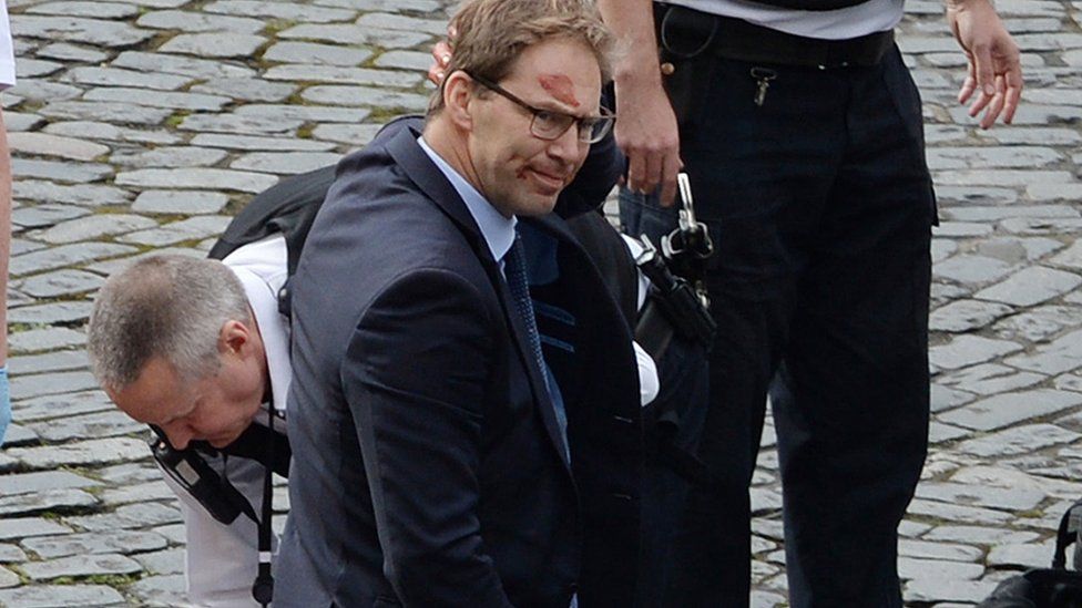 Conservative MP Tobias Ellwood stands amongst the emergency services at the scene outside the Palace of Westminster