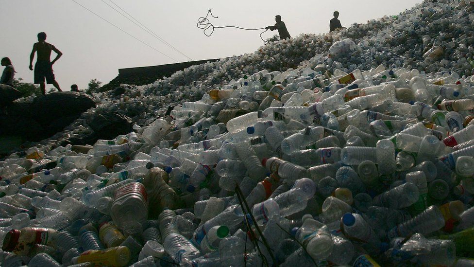Workers on a pile of plastic bottles in China