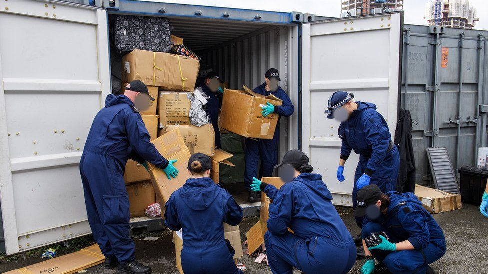 Police officers seizing counterfeit goods from shipping containers