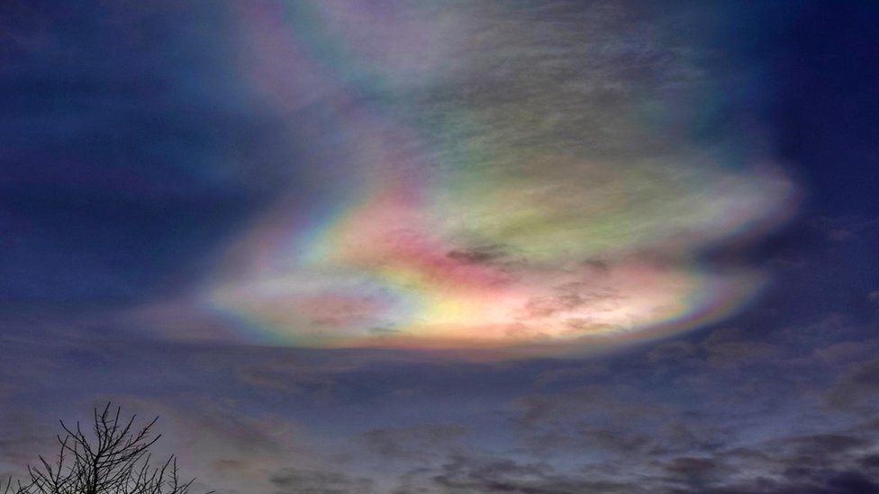 A multi-coloured cloud shines out in a deep blue sky