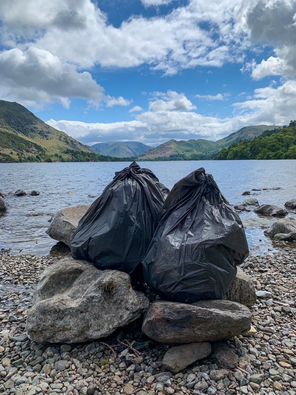 Two bags of rubbish collected at the side of a lake