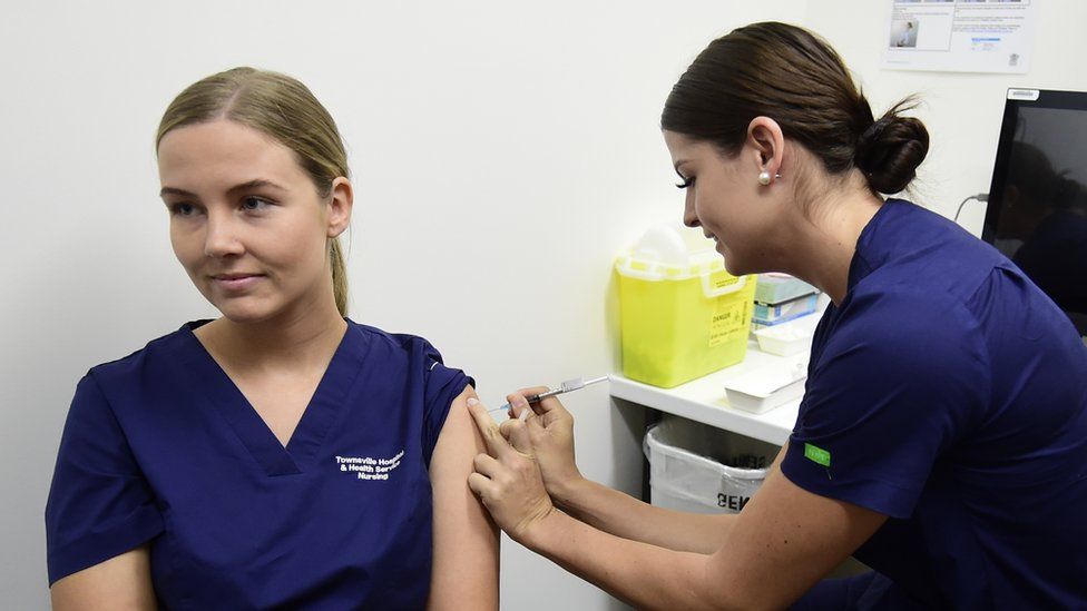 A nurse gives another nurse an injection