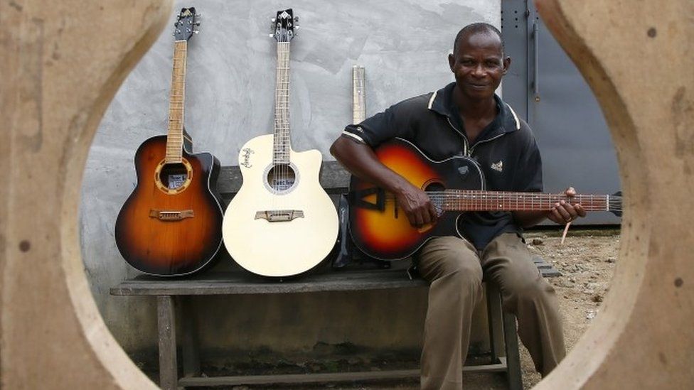 Adicko Pierre, 62, an Ivorian luthier plays a guitar made by him, in the yard of his workshop in Abobo, a district of Abidjan, Ivory Coast, 30 September 2020