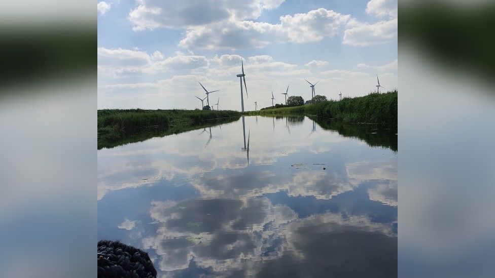 Clouds and a windfarm reflected in water