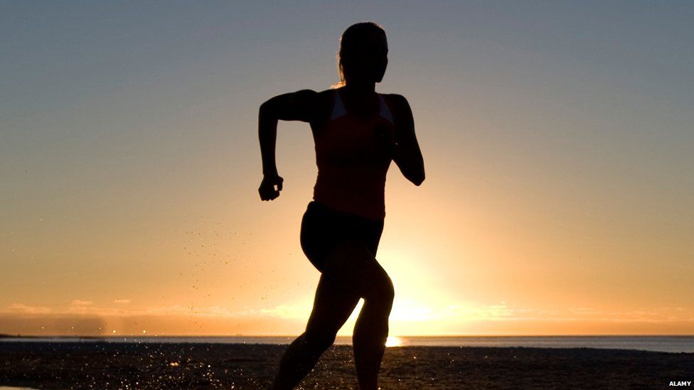 Woman silhouette running against sunset
