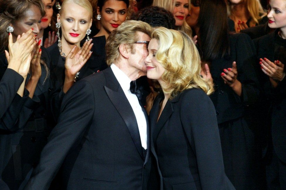 Yves Saint-Laurent (L) kisses Catherine Deneuve in 2002 during his last fashion show