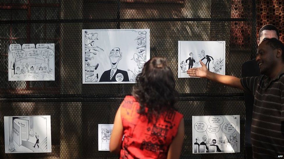 People visit an outdoor exhibition of editorial cartoons and caricatures of US President Barack Obama in Nairobi, Kenya