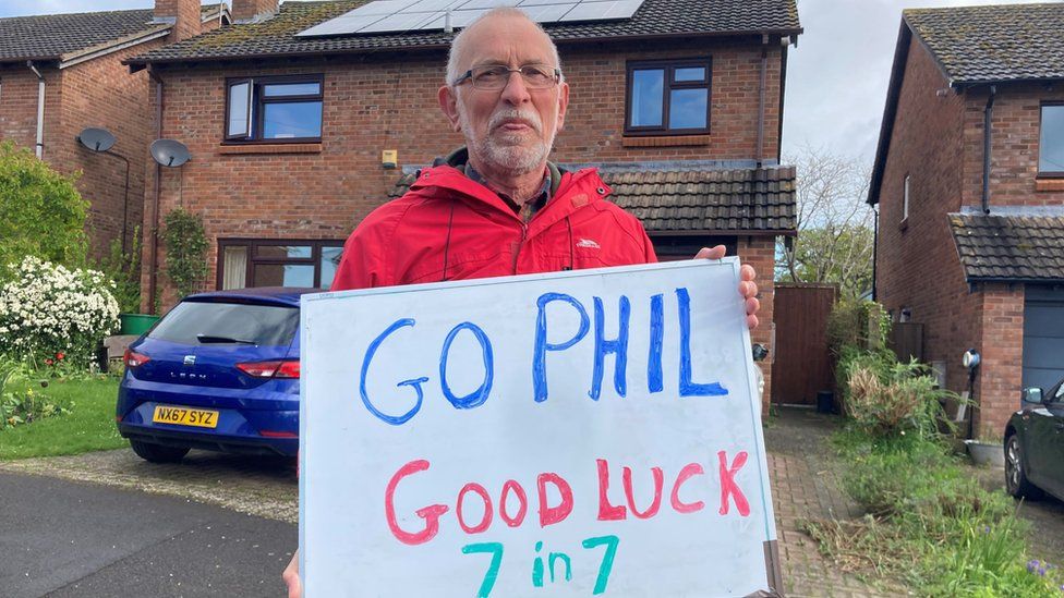 Phil Wiseman's neighbour holding a banner that says Go Phil Good Luck 7 in 7