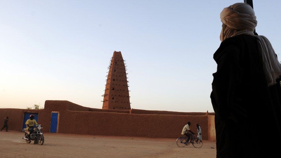 A arts and crafts seller stands in front of the Old Mosque of Agadez in the northern Niger tourist city on September 24, 2010.