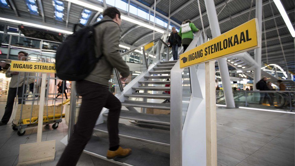 Dutch commuters line up at a polling station to vote in parliamentary elections at Utrecht Central Station, in Utrecht, the Netherlands, 15 March