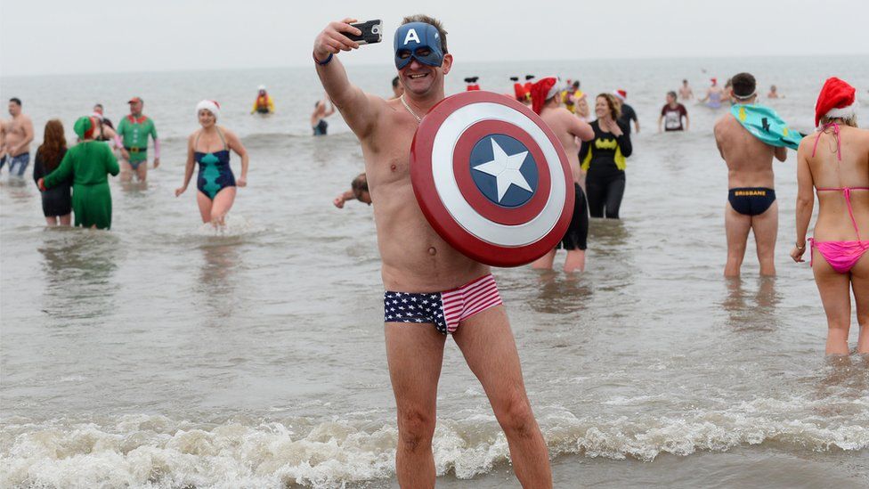 People in fancy dress running into the sea