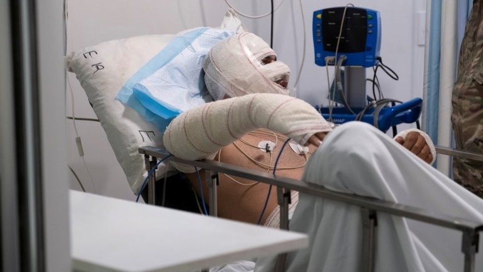 A Lebanese soldier speaks to a man injured in a petrol tank explosion in Akkar at a hospital in Beirut (15 August 2021)