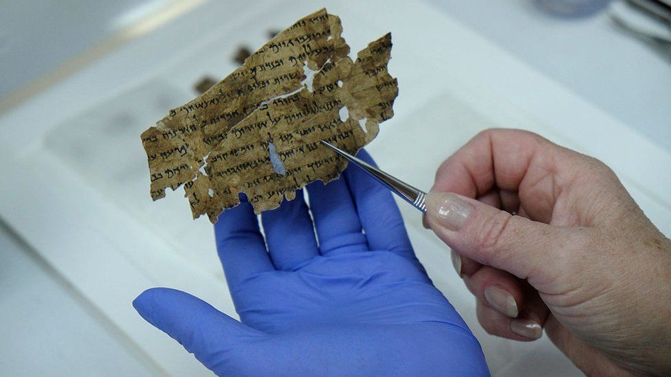A worker of the Israeli Antiquity Authority sews fragments of the Dead Sea scrolls which includes biblical verses in a preservation laboratory of the Israel Museum in Jerusalem