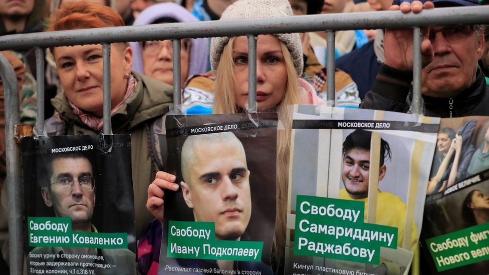 Demonstrators in Moscow hold up posters showing the faces of jailed protesters they demand be freed on Sunday 29 September