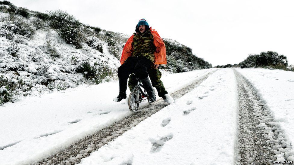 Two people on a bike going down a snowy road