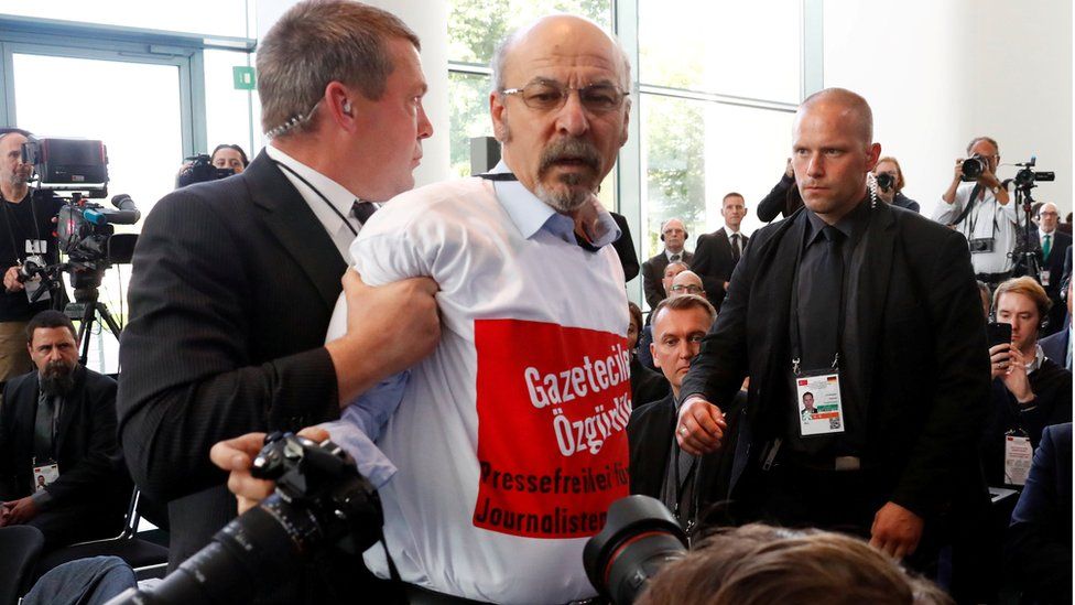 Turkish journalist Ertugrul Yigit from Avrupa Postasi is removed by security guards during a news conference in Berlin, September 28, 2018