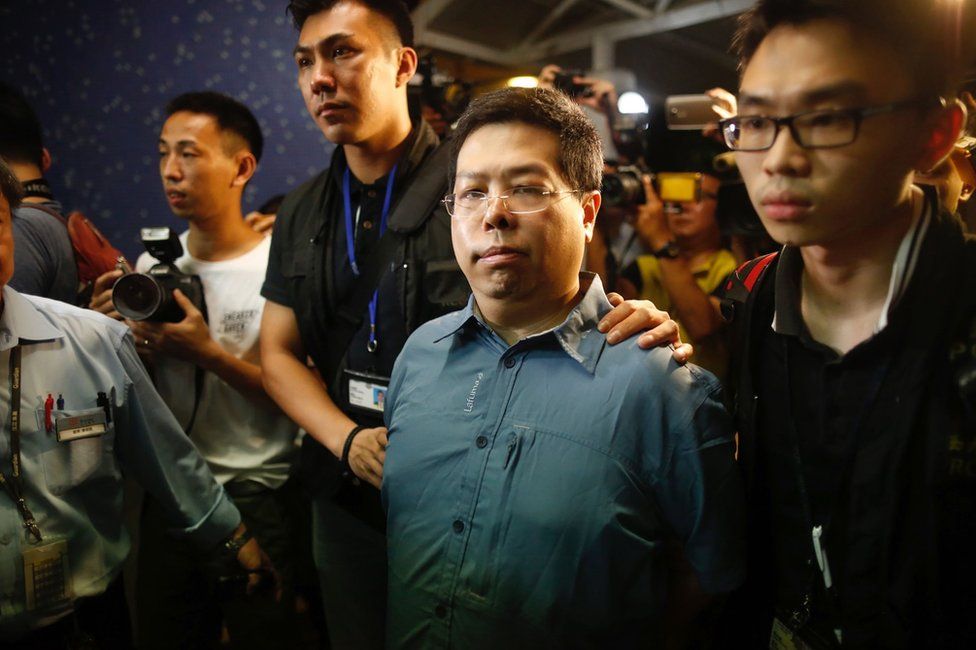 This handout photo from The Initium taken and released on 15 August 2017 shows Democratic Party member Howard Lam (C, blue shirt) after his arrest for "misleading police" in Hong Kong.