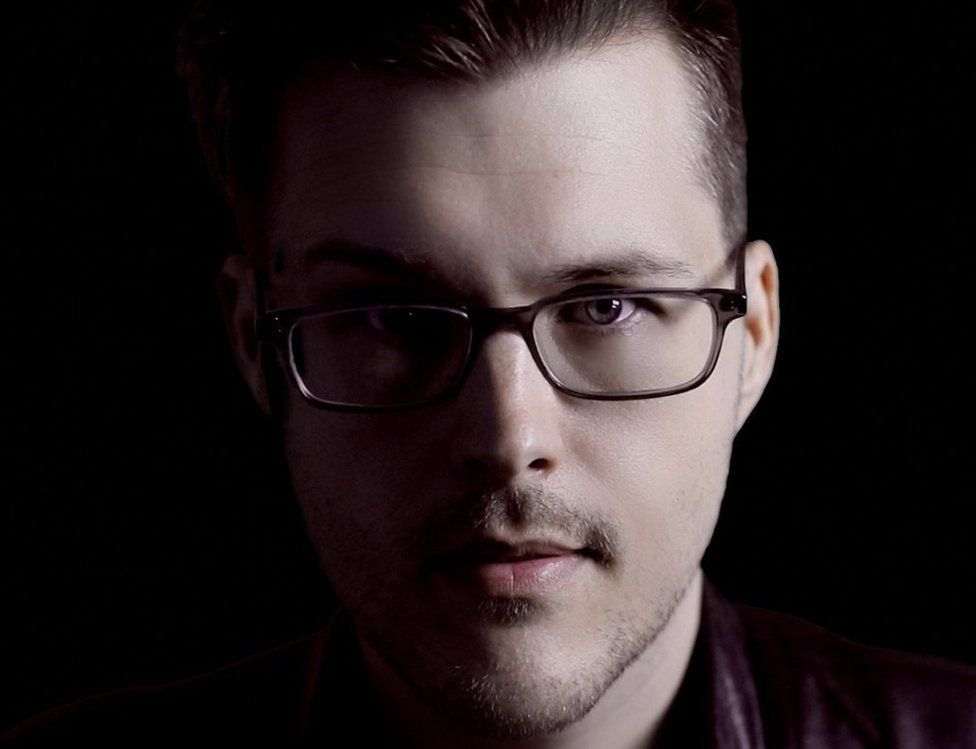 Dave Wiskus, wearing his glasses, is lit in strong highlights and deep shadows in this professional headshot