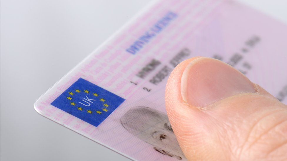 Holding out a driving licence - stock photo