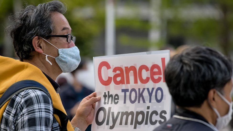 A protester carries a placard during a demonstration against the Tokyo Olympics in front of the New National Stadium, the main stadium for the Tokyo Olympics.