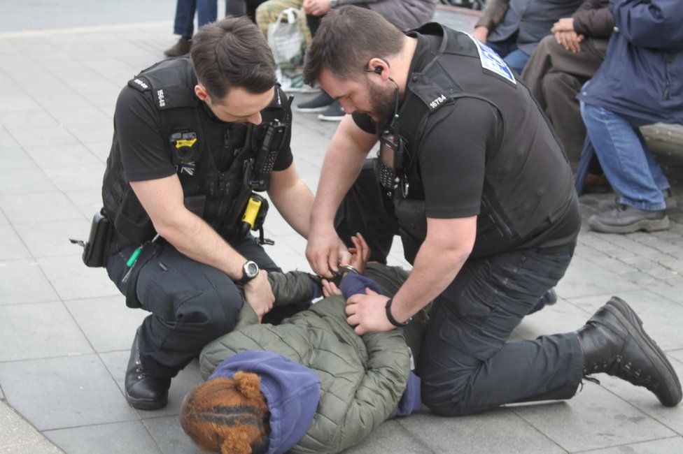 Police arresting a woman for carrying a knife
