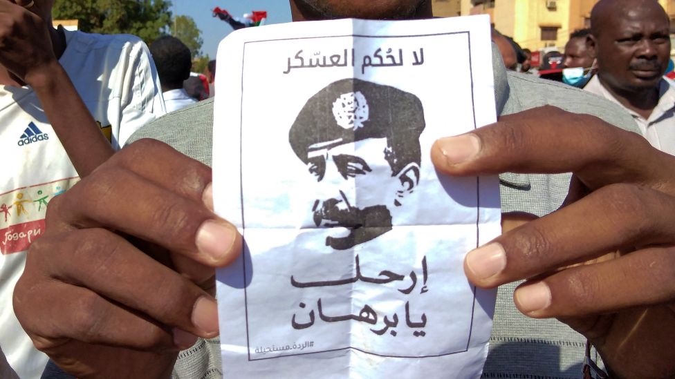 Протестующий против переворота в Омдурмане держит плакат, на котором суданский генерал Абдель Фаттах аль-Бурхан читает: «Нет военному правилу» - 17 ноября 2021 г.
