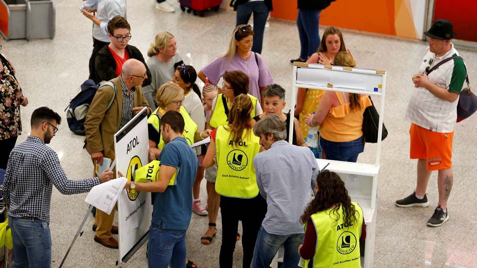 Passengers talk to Civil Aviation Authority employees at Mallorca Airport as an announcement is expected on the Thomas Cook's tour operator, in Palma, Majorca