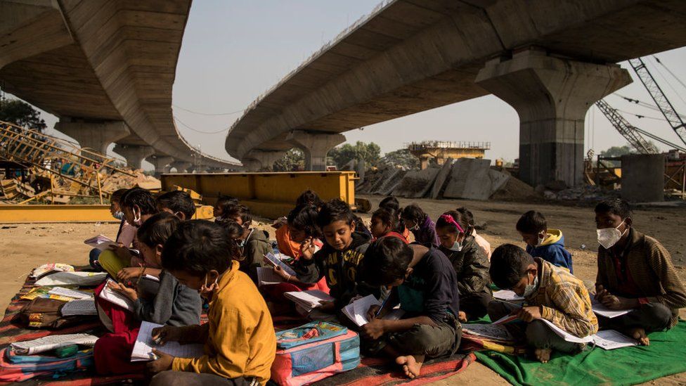 Underprivileged children study while seated on mats on the ground at an improvised classroom set up at a construction site on December 09, 2020 in New Delhi,
