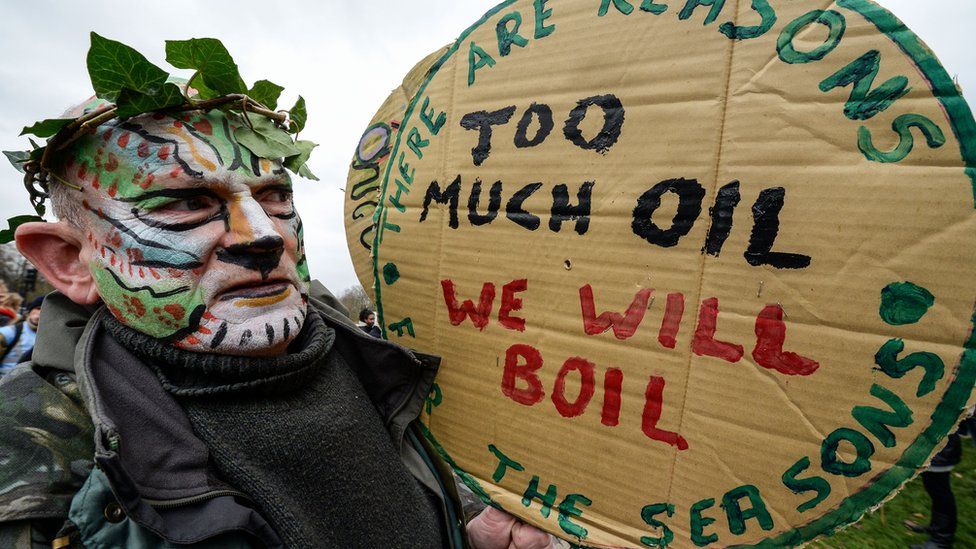A protester dressed as the green man prepares to march during the London Climate March on 29 November 2015