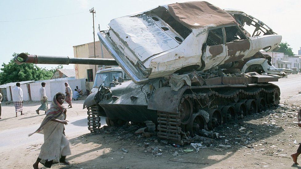 A wrecked car lies on top of a burned-out tank on a main street during the Somali civil war. In the 1980s a internal fighting began when warlord factions joined together to overthrow then president Siad Barre, who finally lost power in 1991