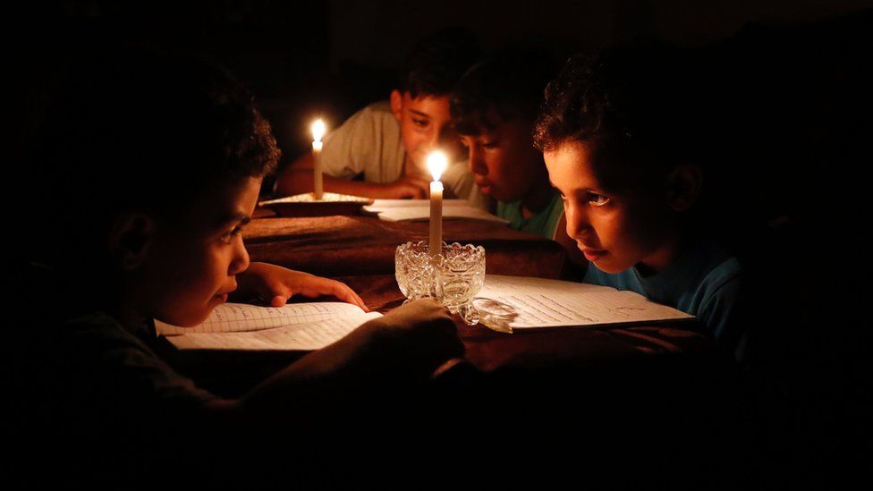 Palestinian children at home reading books by candle light because of electricity shortages in Gaza City.