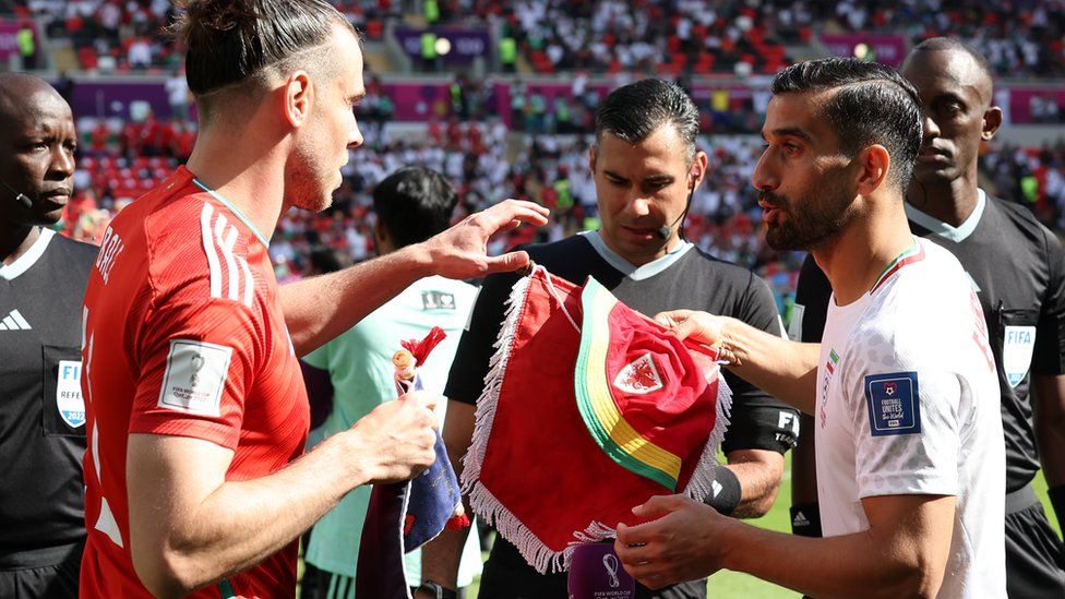 Gareth Bale handing bucket hat to Iran captain Ehsan Hajisafi