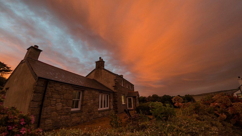 A house with orange cloudy lights above it